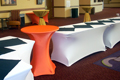 white spandex linens with an orange cocktail table